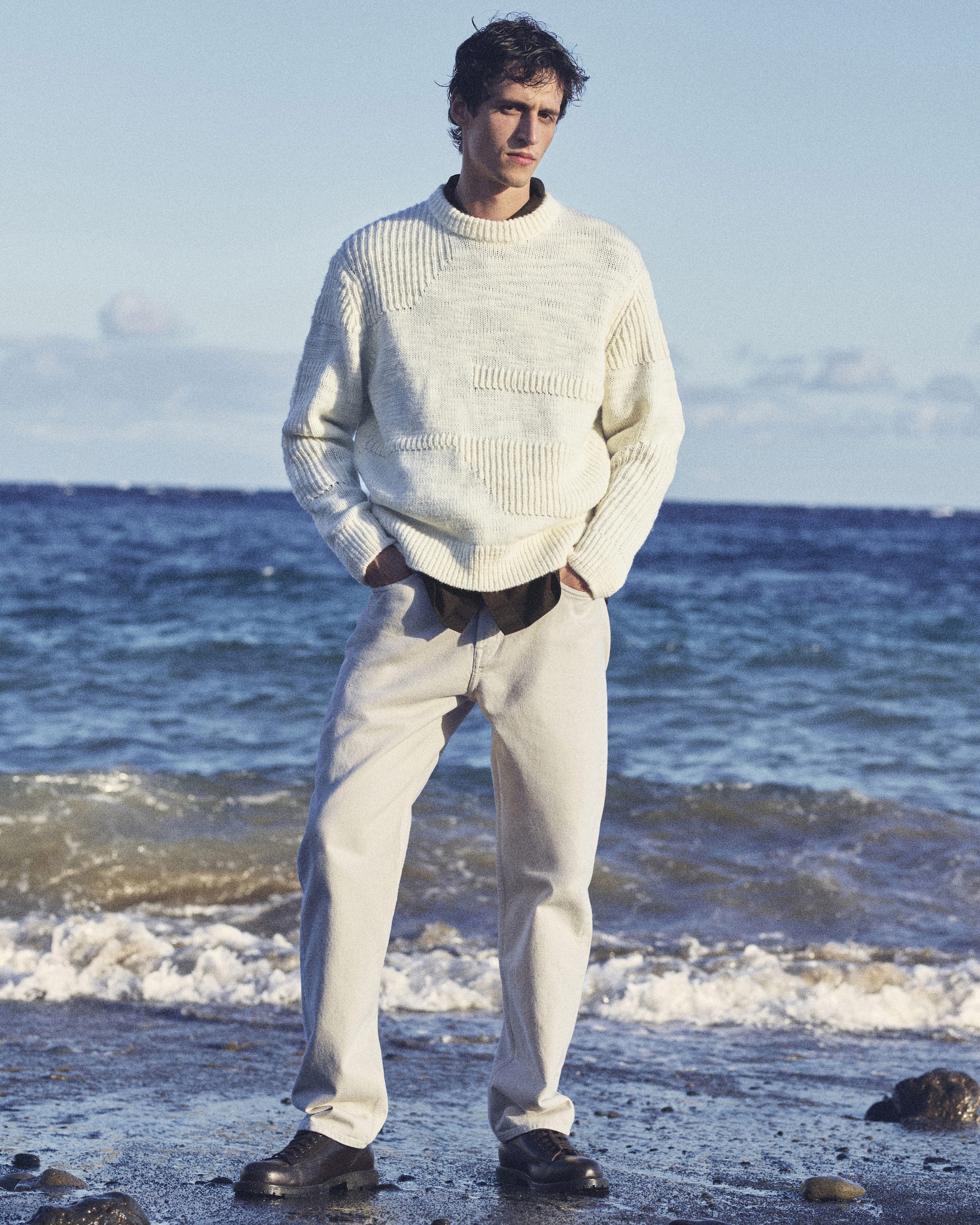 Man in a white outfit in front of the sea