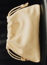 Placeholder for: A beige drawstring pouch lying on a dark surface, showcasing its soft leather texture and simple design.