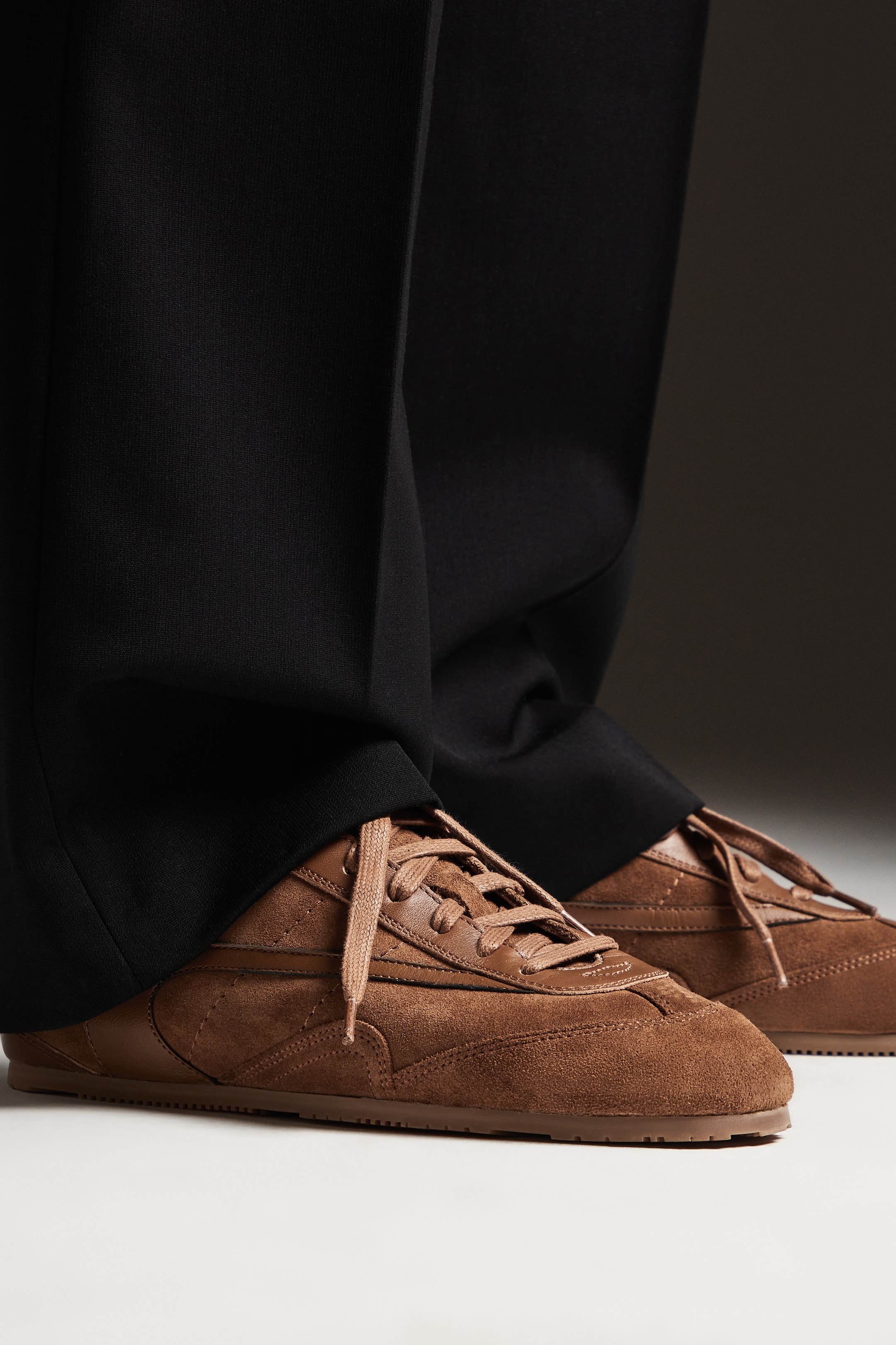 Person wearing black trousers and brown trainers