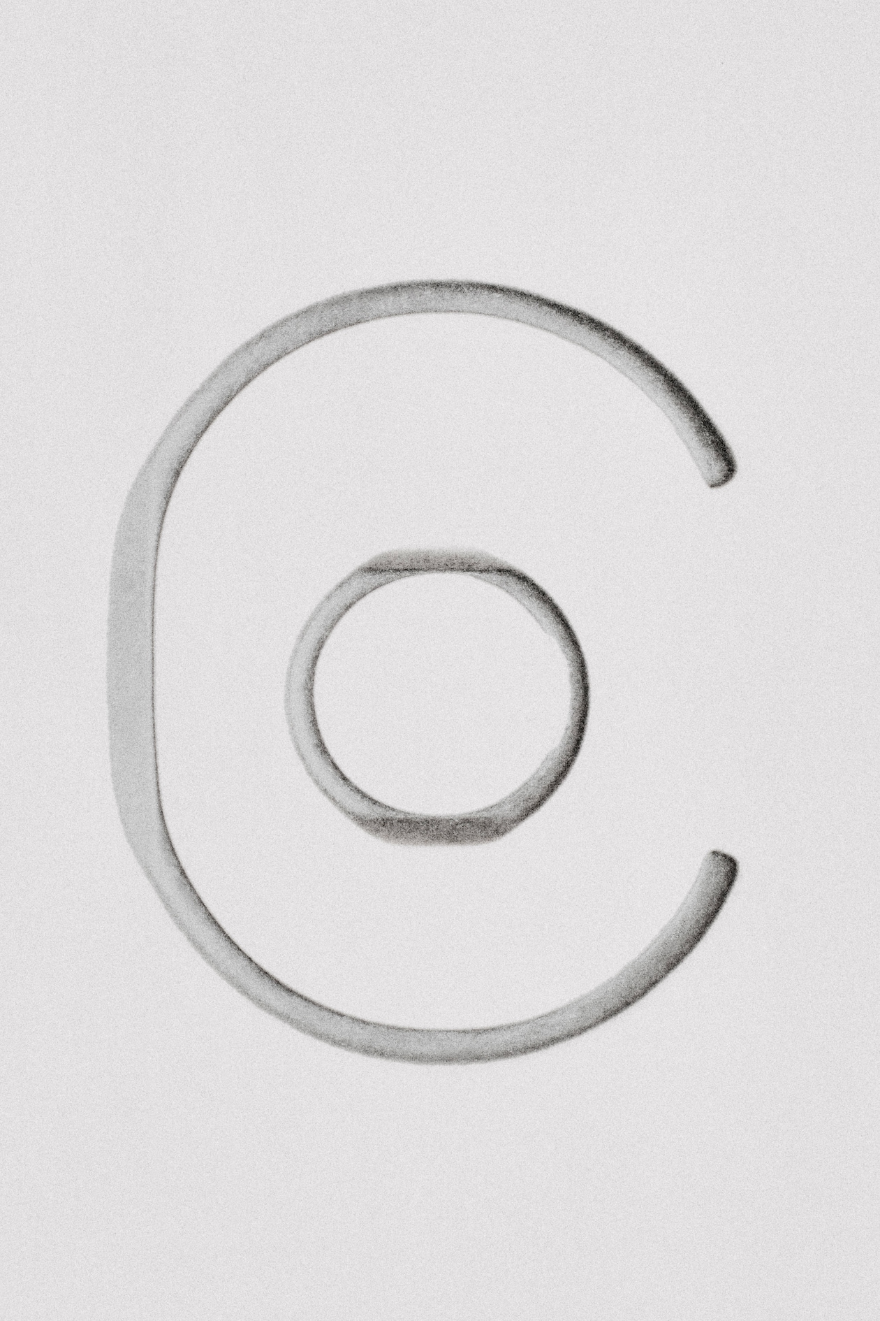 Charcoal sketch of a large open C shape encircling a smaller imperfect ring on a white background.