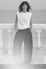 Placeholder for: woman in white sleeveless top and black wide leg trousers