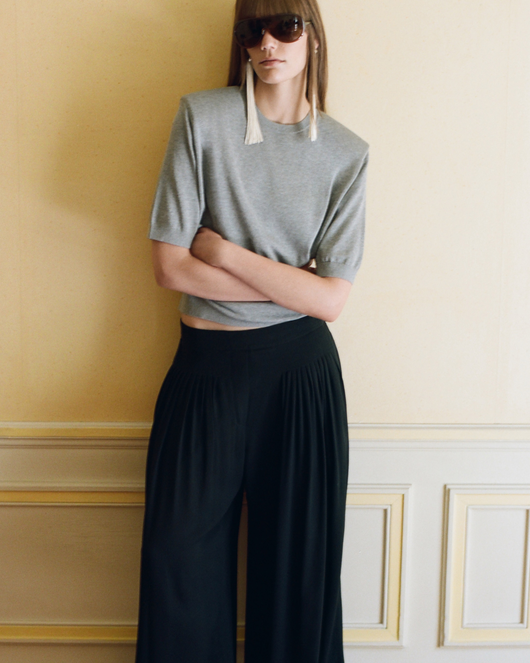 model wearing grey top and black trousers