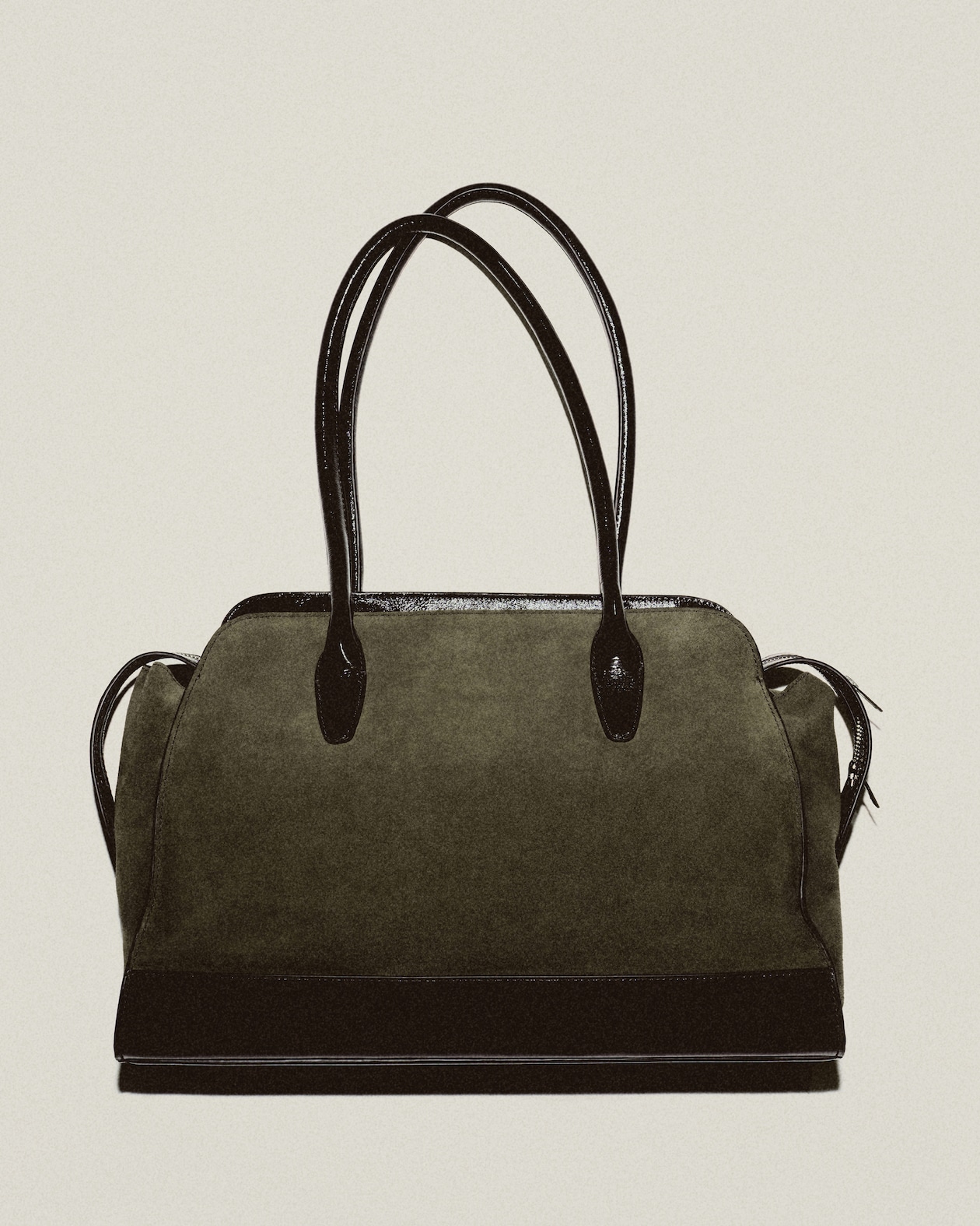 A stylish olive green handbag with black leather handles and accents, featuring a structured design and a zipper closure.