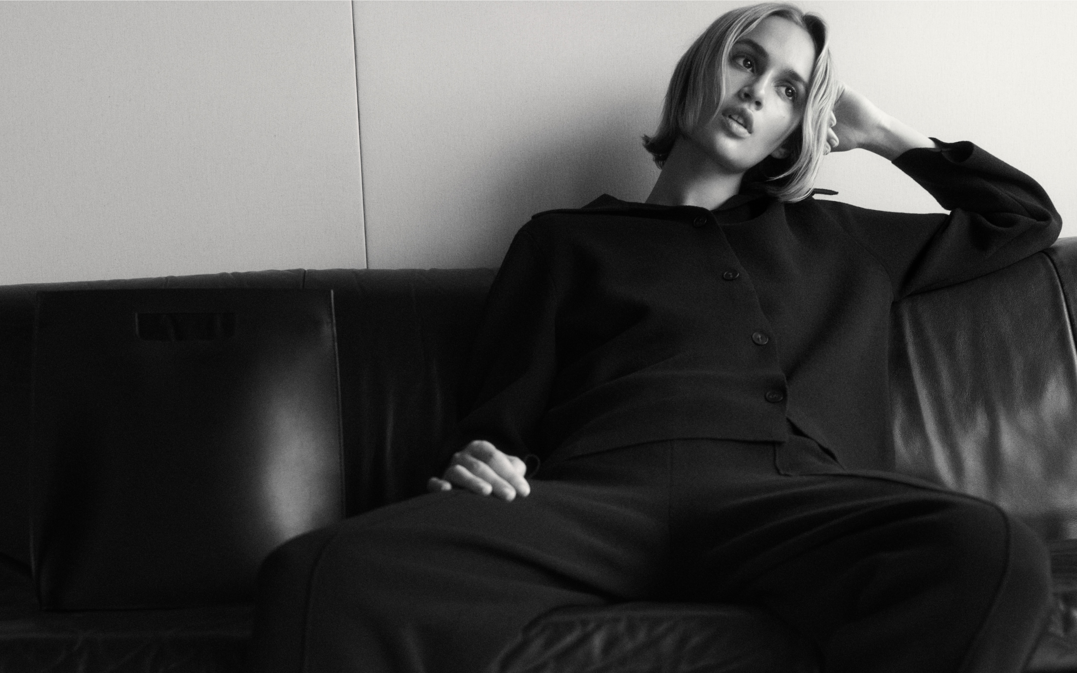 model wearing black sitting on leather sofa