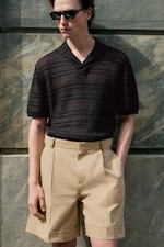 Placeholder for: man wearing a knitted brown and black polo shirt with beige chinos shorts