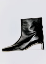 Placeholder for: A sleek black leather ankle boot with a pointed toe and a low heel, displayed against a white background.