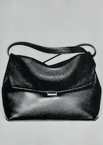 Placeholder for: Black leather handbag with a smooth texture and a curved top handle, displayed against a plain background.