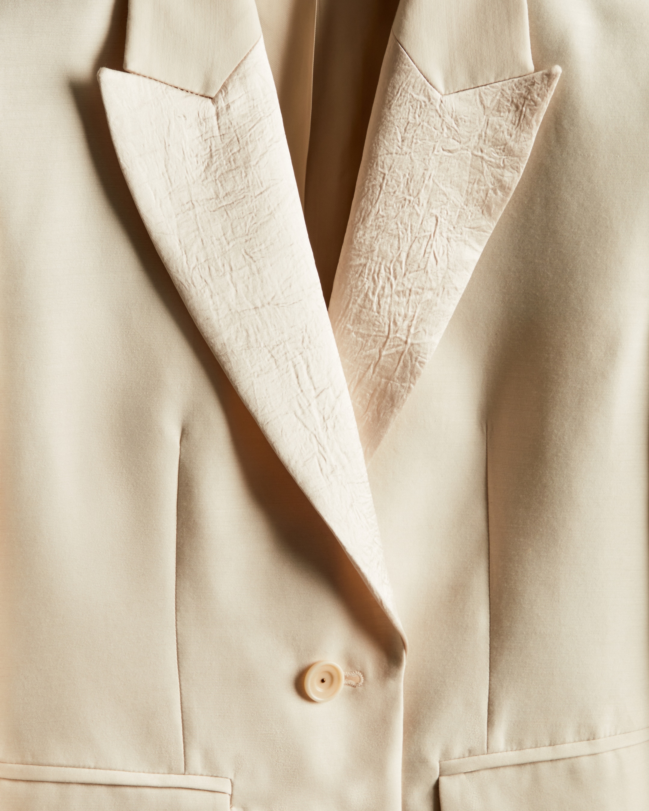 close up of cream blazer with silk panels