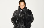 Placeholder for: Person wearing a dark, plush fur coat, looking directly at the camera against a plain white background.