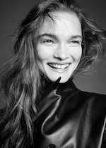 Placeholder for: Black and white photo of a smiling person with loose hair, wearing a dark leather jacket.