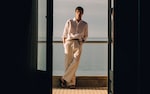 Placeholder for: man standing on a balcony in a linen shirt and tan pants