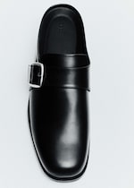 Placeholder for: A black leather shoe with a shiny finish and a side buckle, viewed from above on a light background.
