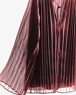 Placeholder for: Close-up of a burgundy pleated dress with a tie detail at the neckline, displaying flowing fabric and elegant draping.