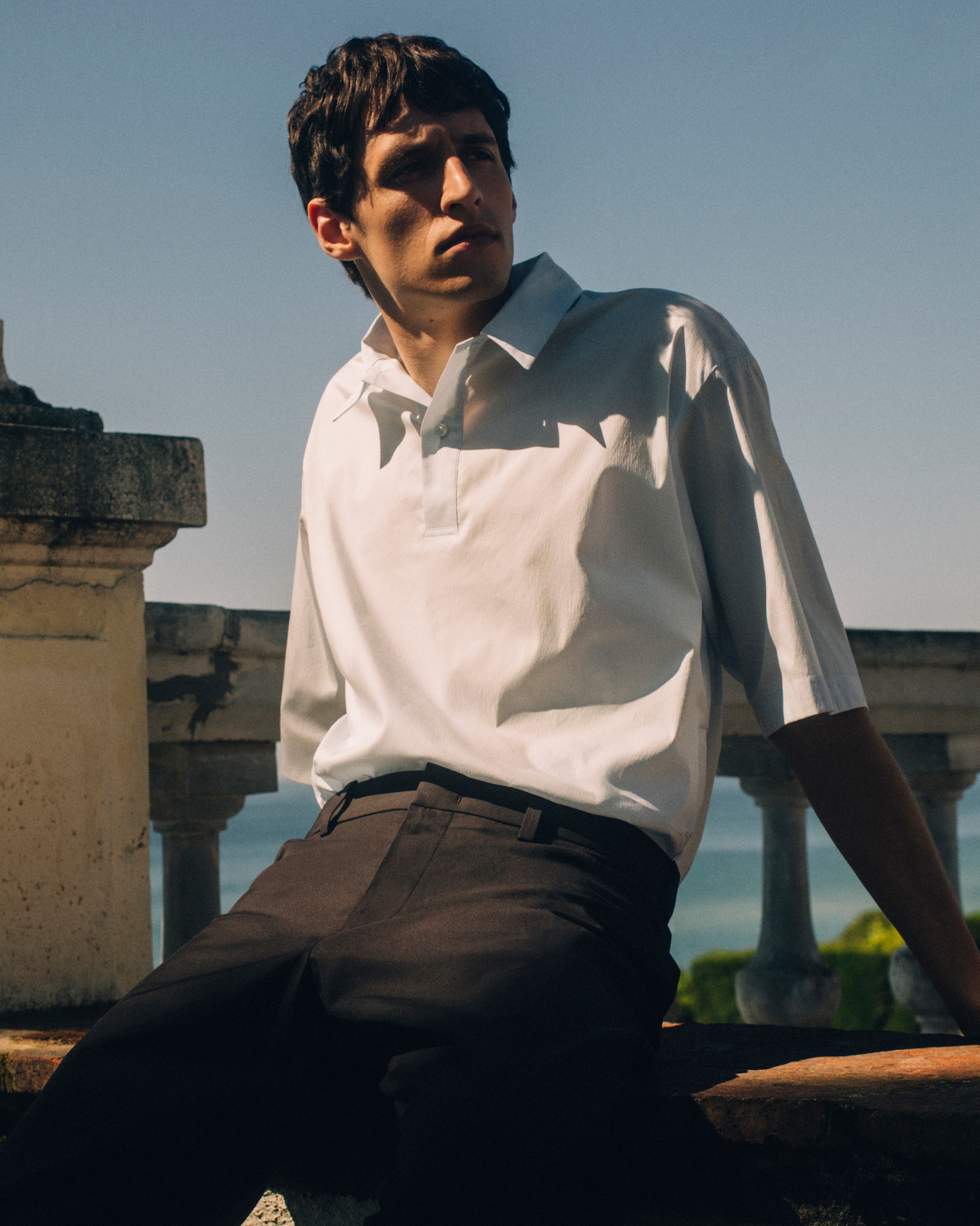 Man in white shirt and brown trousers leaning back
