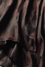 Placeholder for: Close-up of dark, glossy fabric with soft, flowing folds and a smooth texture, creating a luxurious appearance.