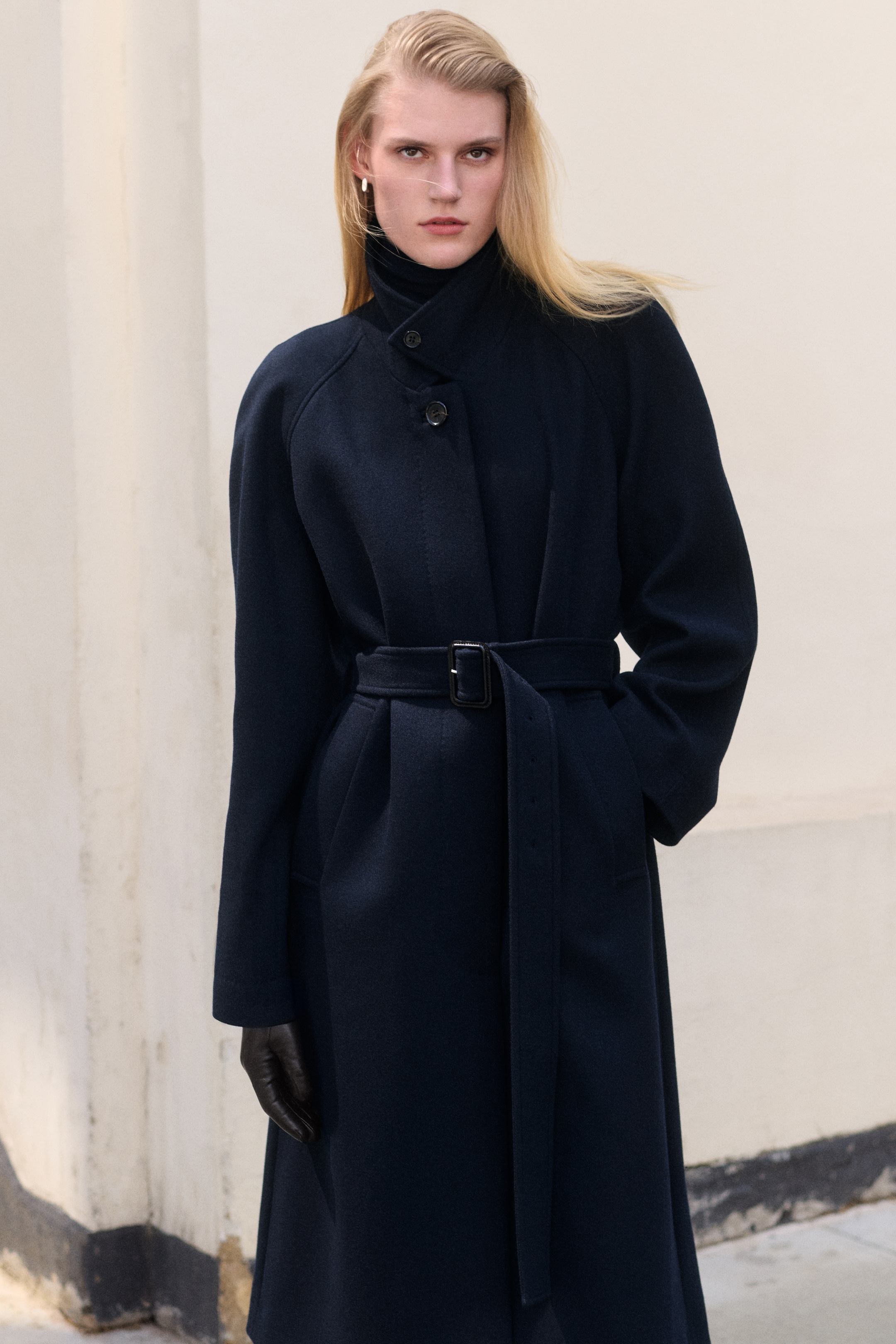 Women in a long sleeve black coat and belt