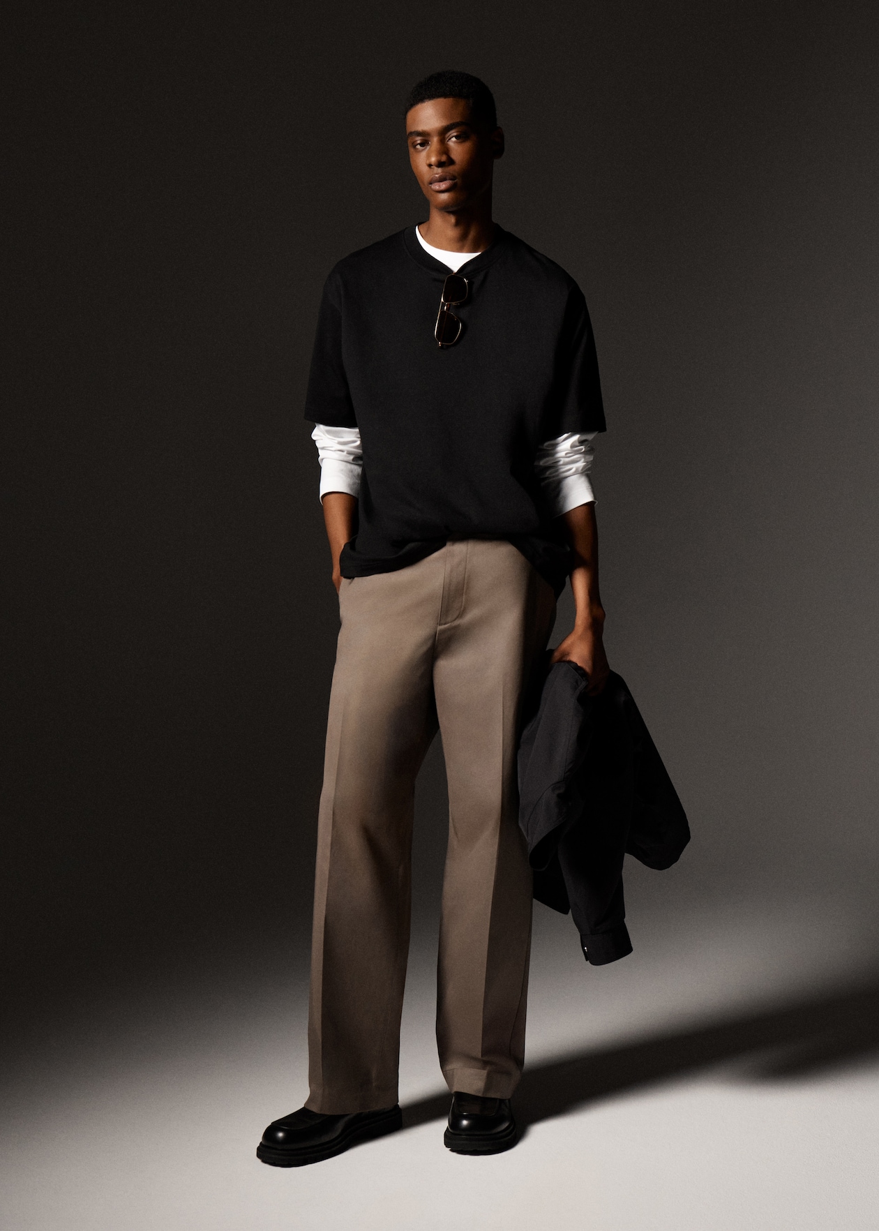 Man in brown trousers & black wool jumper over a white long sleeved shirt
