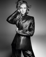 Placeholder for: Model wearing a sleek, double-breasted leather suit poses with one hand touching her hair in a dramatic black and white portrait.