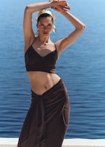 Placeholder for: woman in brown top and wrap skirt with head scarf