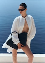 Placeholder for: woman in white pleated shirt with straw bag and sunglasses