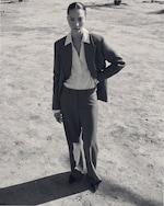 Placeholder for: A person in a suit stands confidently on a barren, sandy ground, casting a shadow. The photo is in black and white.