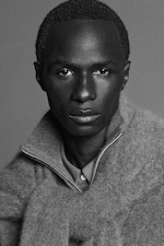 Placeholder for: Black and white portrait of a person with short hair, wearing a textured sweater with a zipper, looking directly at the camera.