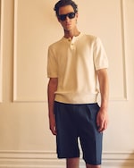Placeholder for: Man standing with a collared knitted top on, navy trousers & sunglasses