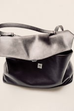 Placeholder for: Sleek black leather handbag with an adjustable strap and a simple clasp, resting against a neutral background.