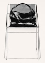Placeholder for: A shiny black handbag placed on a modern wireframe chair with a perforated metal seat and backrest.