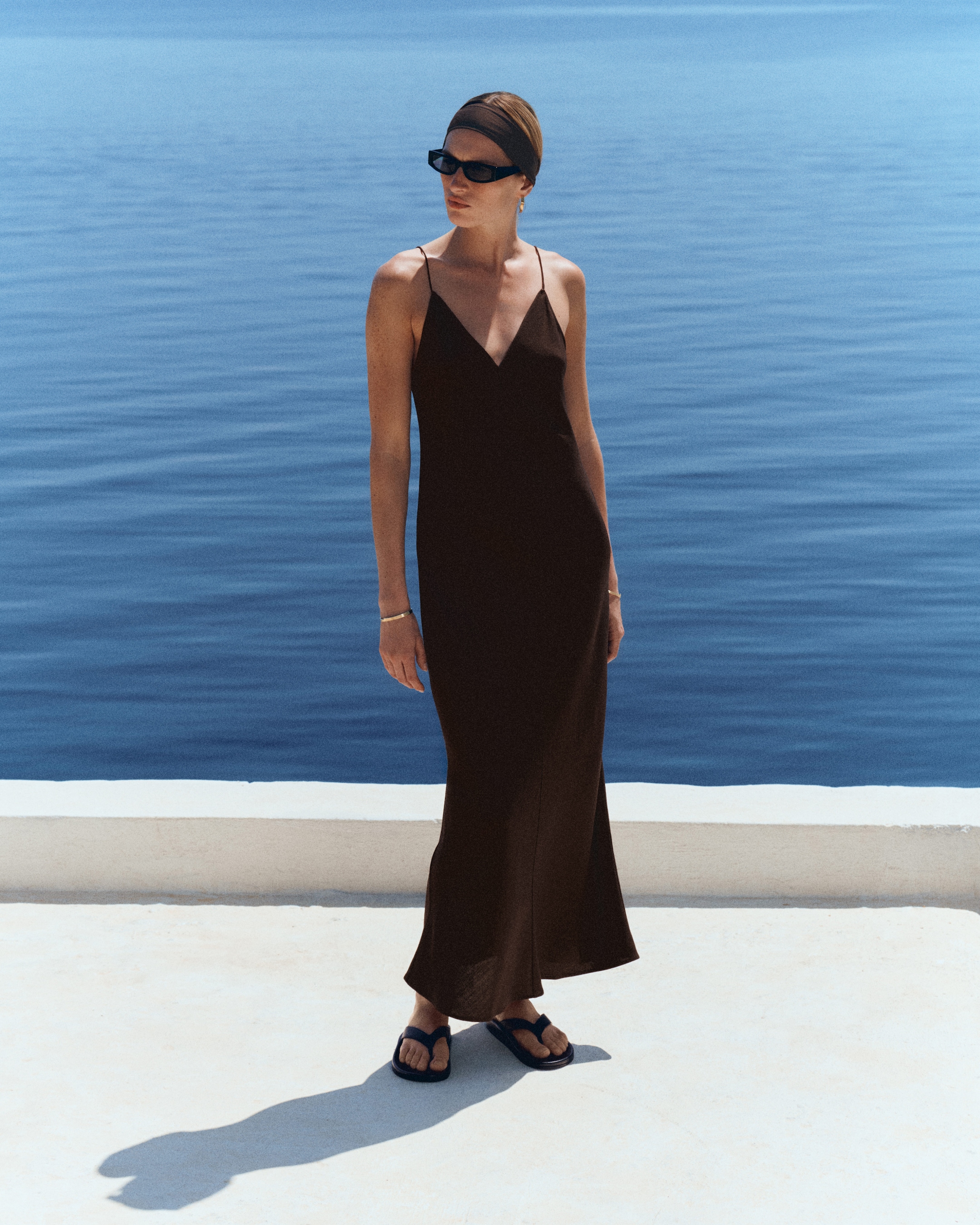 woman in brown sleeveless dress, headband and sunglasses