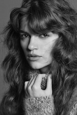 Placeholder for: Black and white portrait of a woman with long, wavy hair, looking thoughtfully at the camera, wearing a cozy knitted sweater.