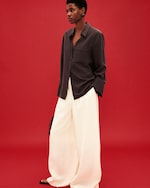 Placeholder for: Red background with white trousers and brown button up shirt