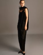 Placeholder for: A woman wearing an elegant black outfit with fringe details and a matching scarf, posing against a neutral background.