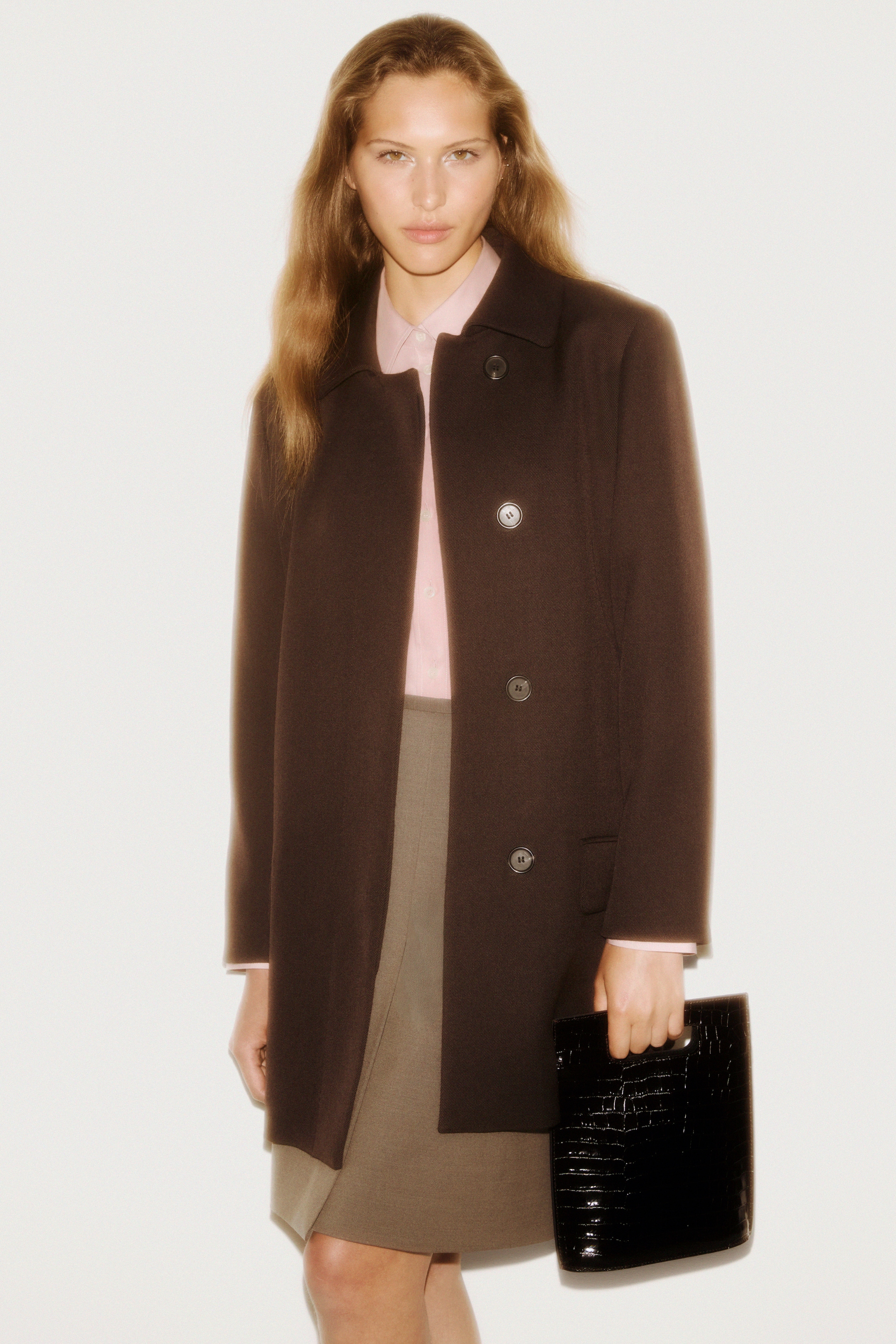 Women in brown jacket, jacket, and blakc skin bag