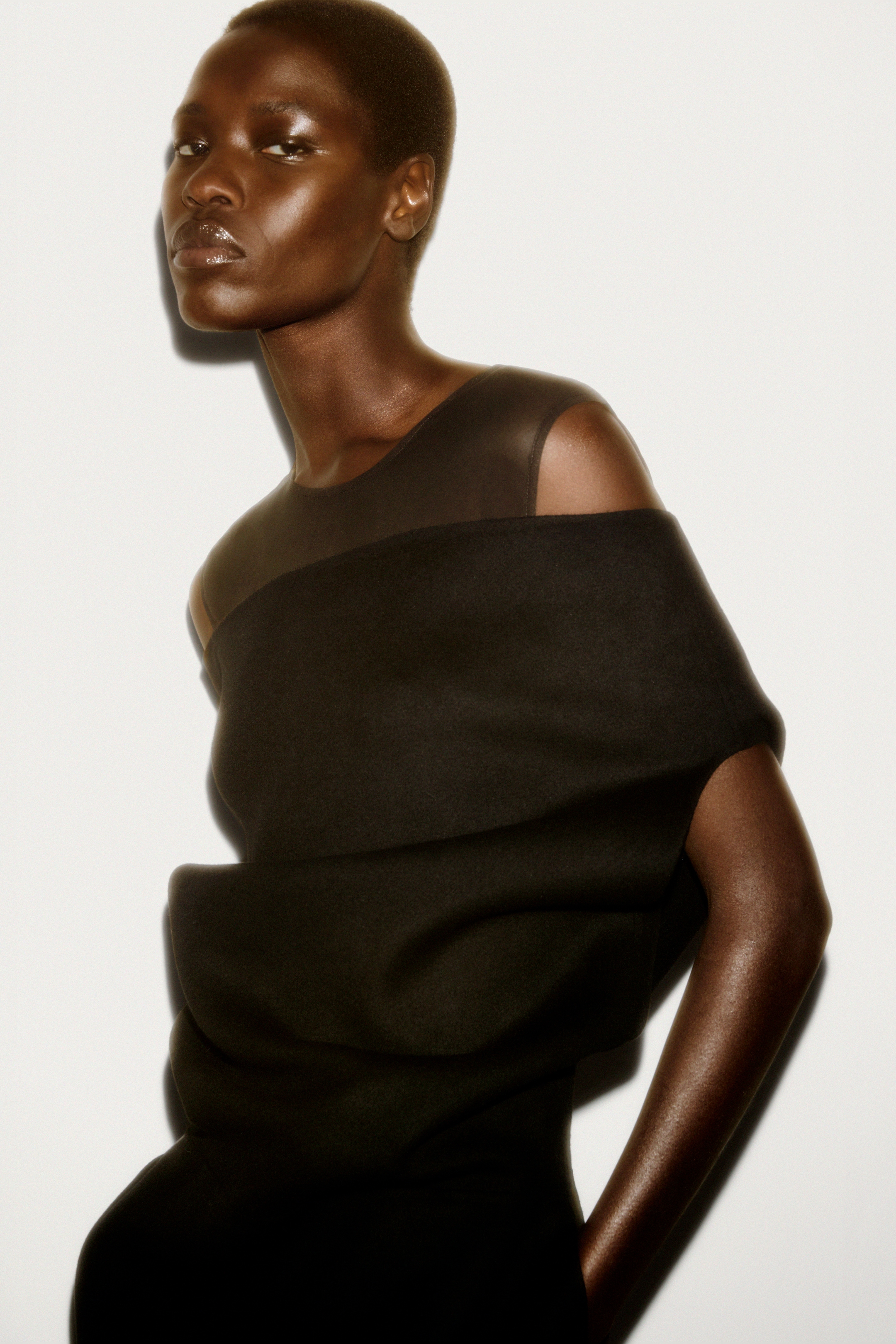 Woman in vest top & off the shoulder jumper with her hands in her pockets