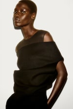 Placeholder for: Woman in vest top & off the shoulder jumper with her hands in her pockets