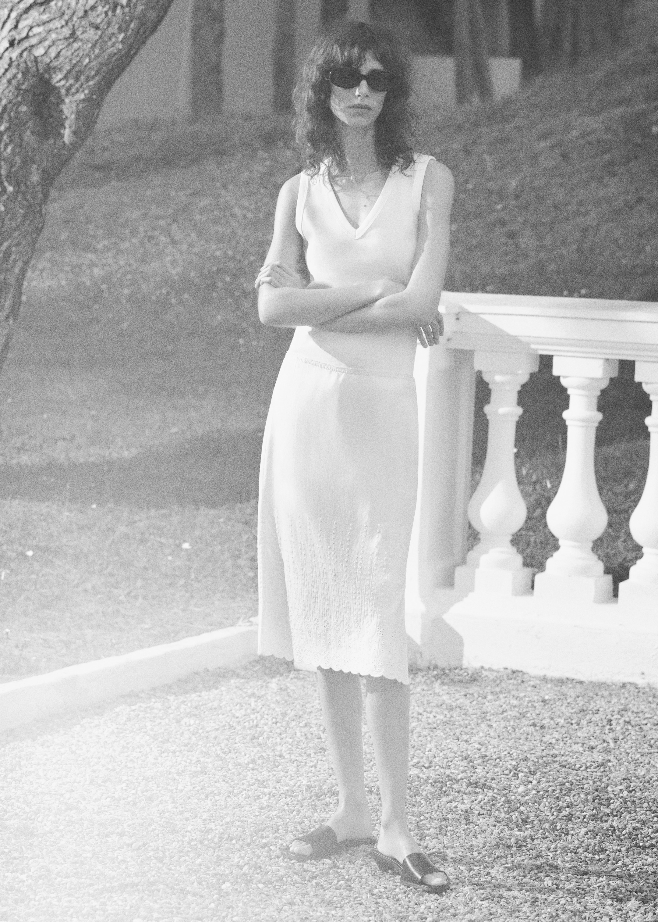 woman in white tank top and midi skirt with sunglasses and heels