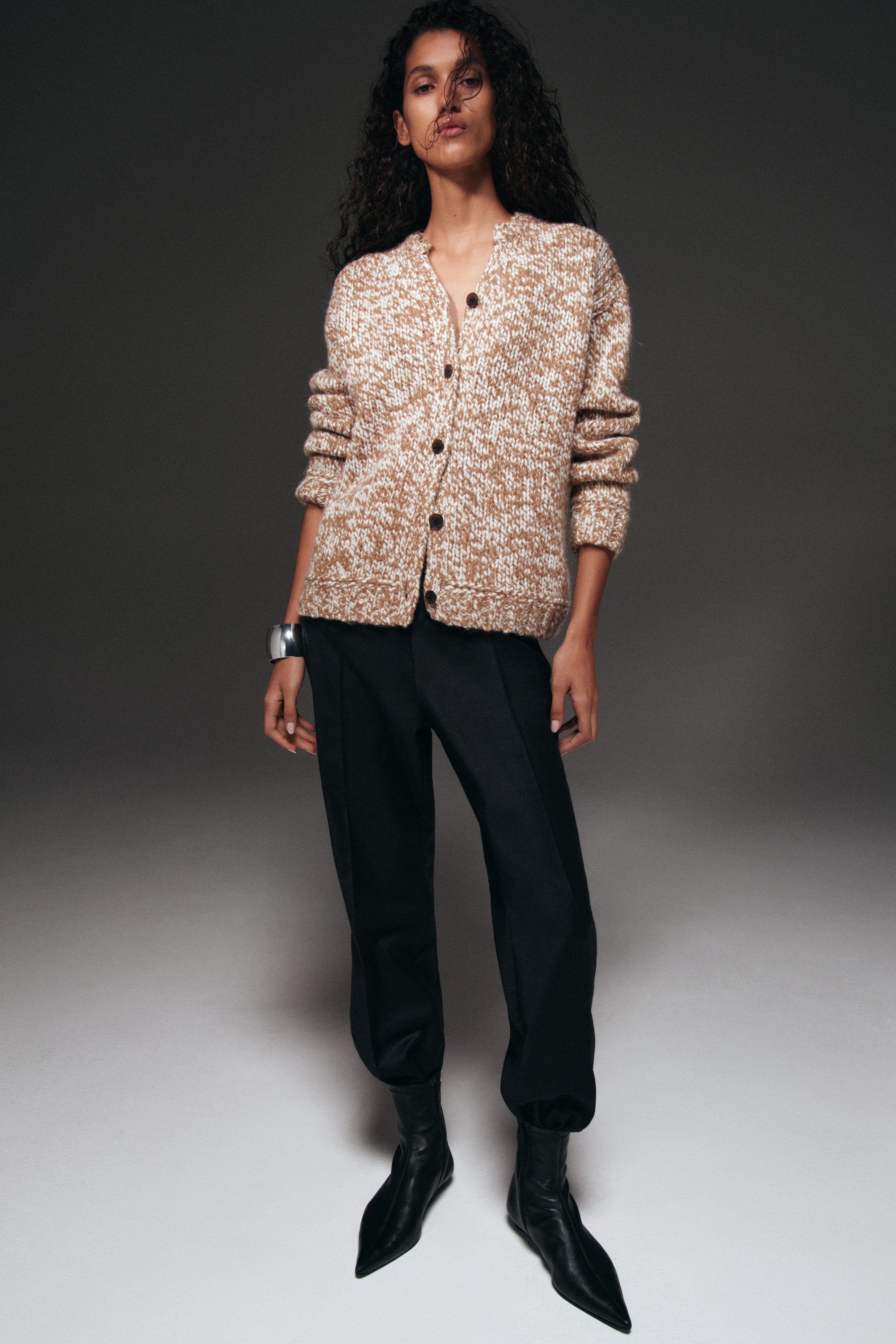 woman in beige cardigan and black trousers