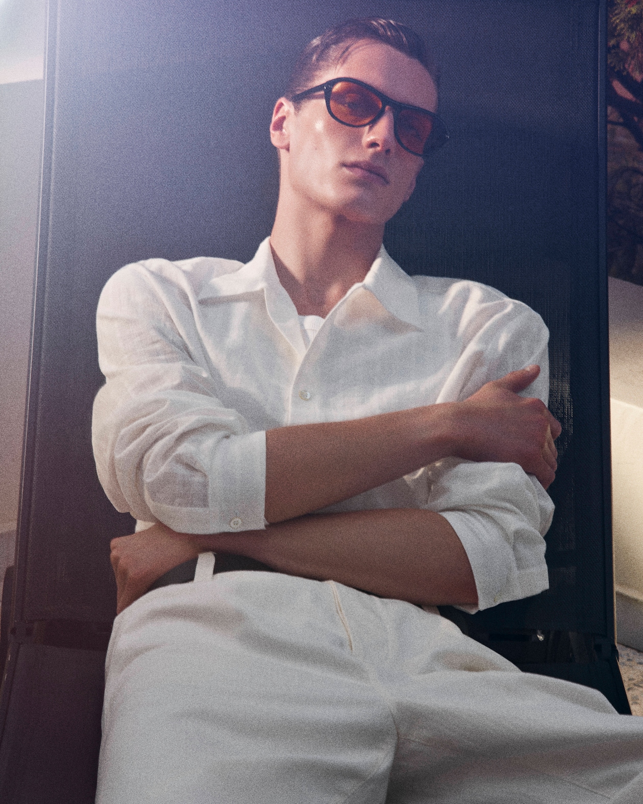man in white shirt leaning back in chair wearing sunglasses