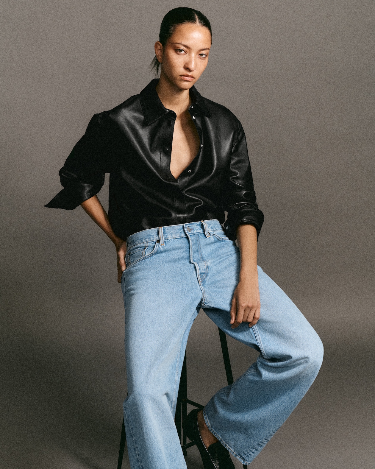 Model in black leather button up and light wash jeans