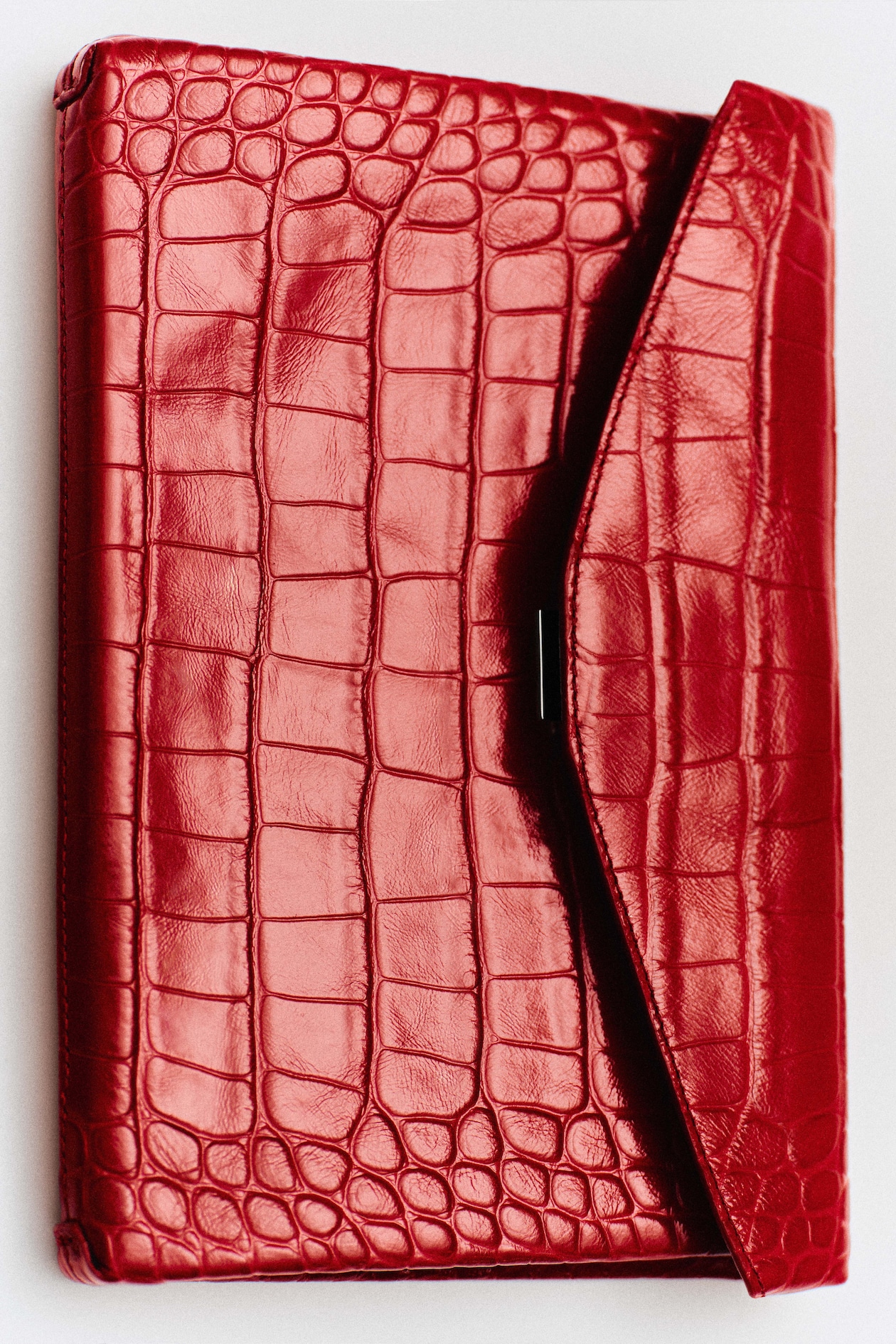 A red crocodile pattern leather envelope clutch with a sleek, shiny finish.