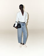 Placeholder for: woman in white v-neck shirt with blue jeans holding a black bag with white shoes