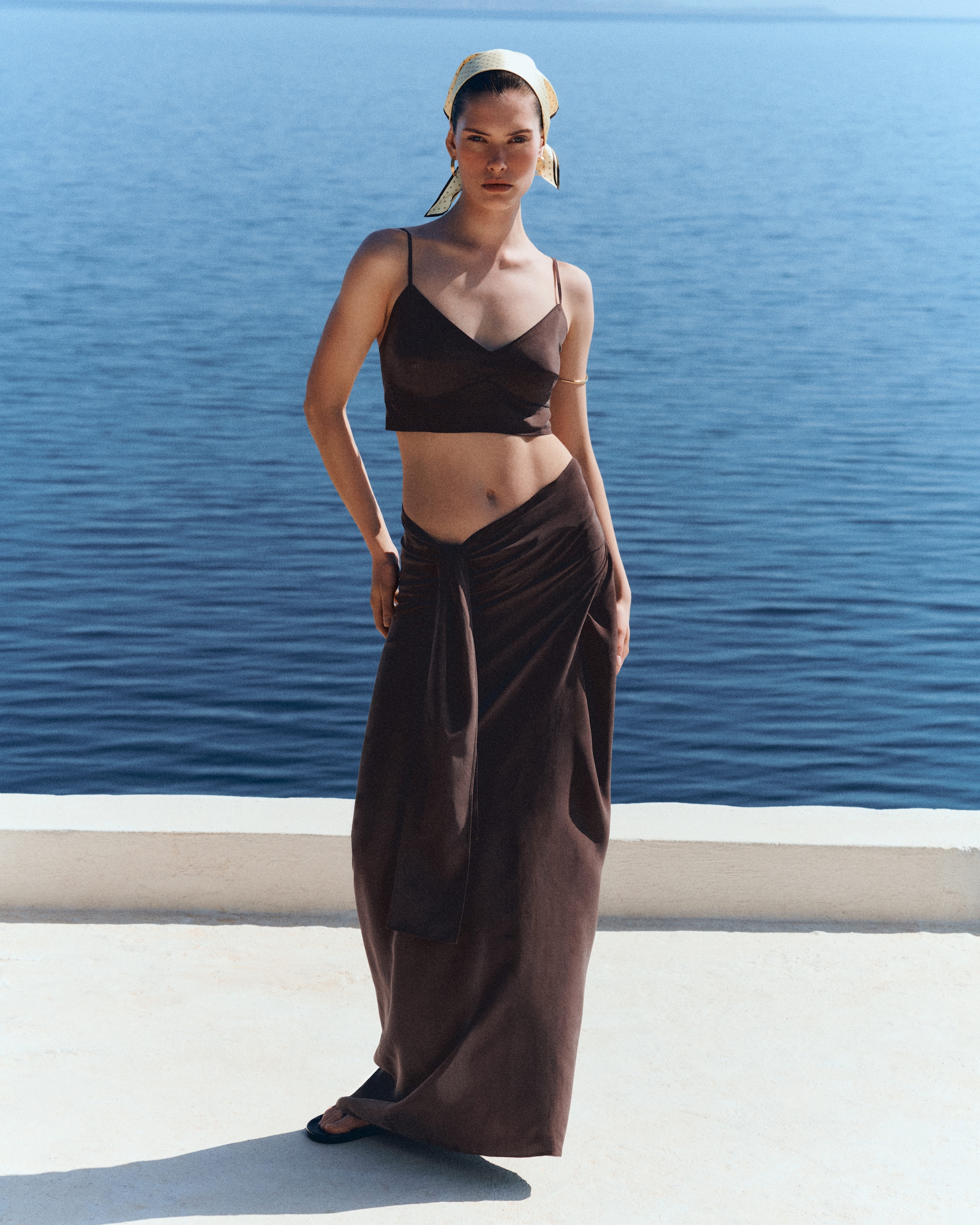 woman in silk bralette and matching skirt by the sea