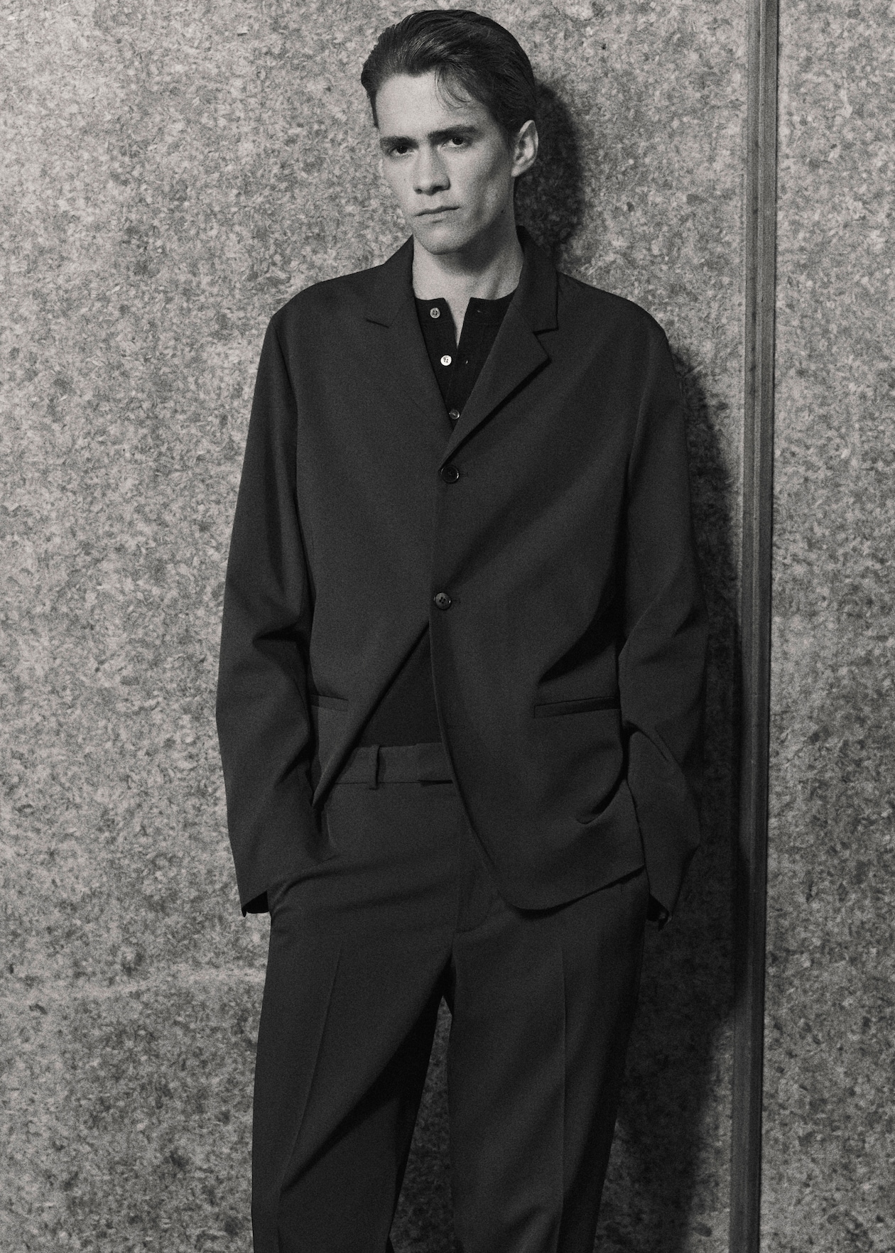 black and white photo. man with combover wearing relaxed suit with henley tshirt underneath