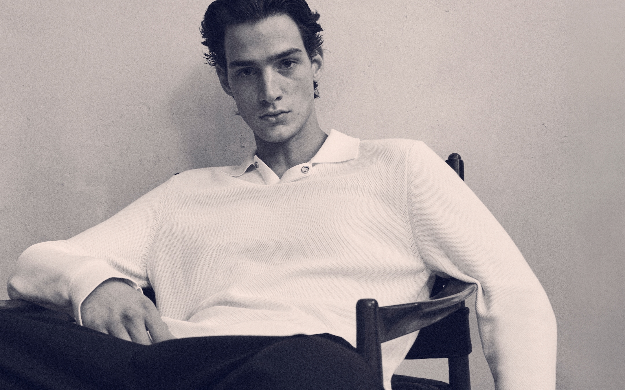 person sitting in a chair with a white knit polo shirt