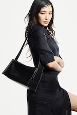 Placeholder for: a person with wet hair, wearing a dark outfit and looking with a serious expression.