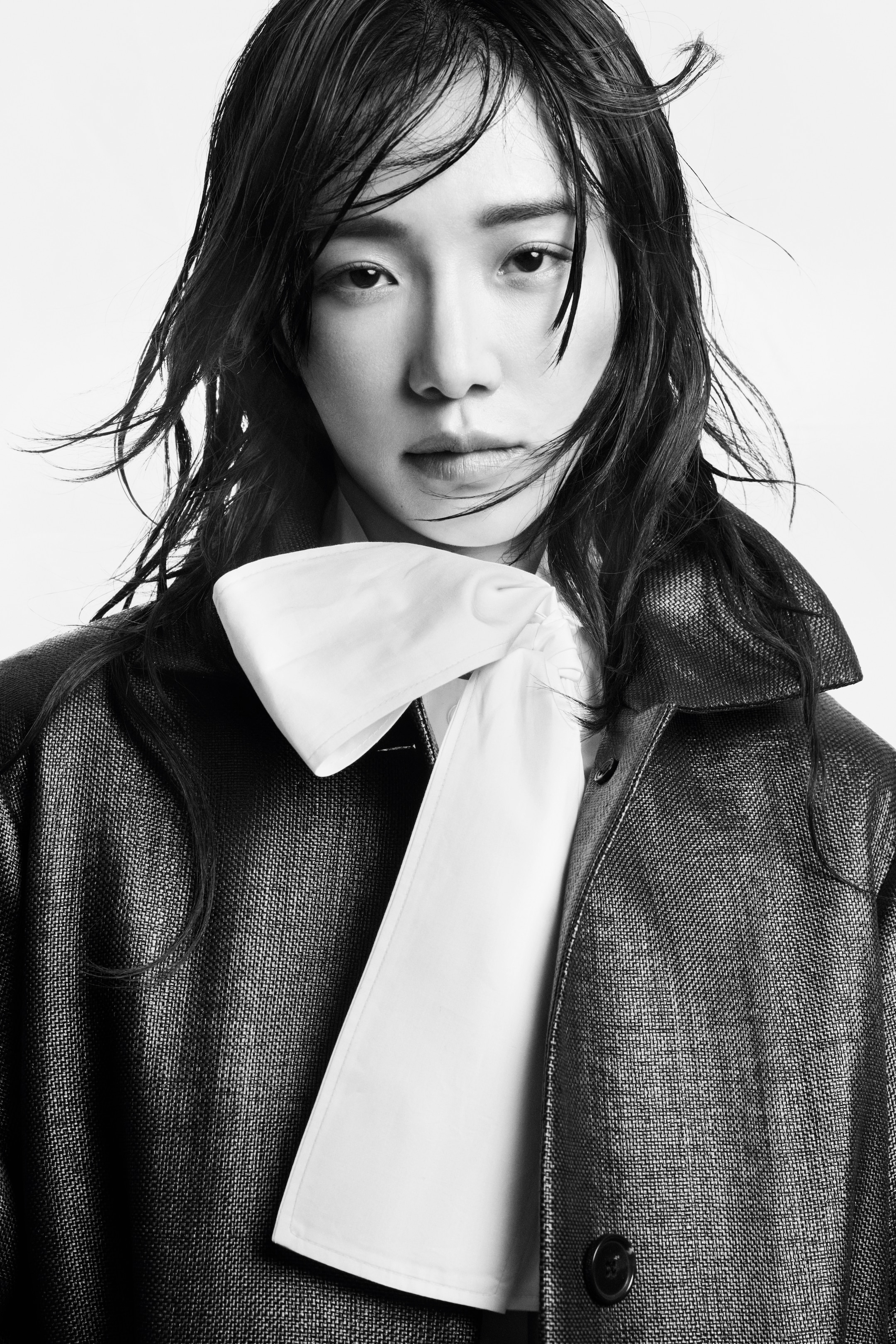 a person with wet hair, wearing a dark outfit and looking with a serious expression.