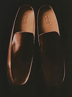 Placeholder for: Brown leather loafers with "COS" embossed on the insoles, set against a dark background.
