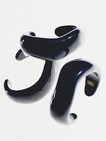 Placeholder for: Three glossy, abstract, black sculptural forms with curving shapes arranged on a white background. One shows a small COS logo.