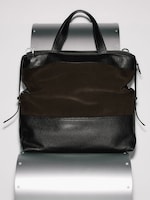 Placeholder for: A sleek black and brown leather tote bag with double handles, displayed against a metallic background.